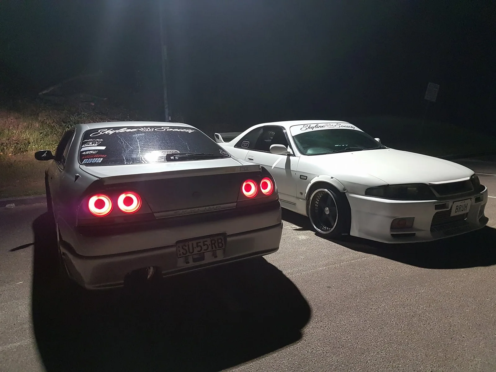 Silver and white Skyline Society coupes parked together at night