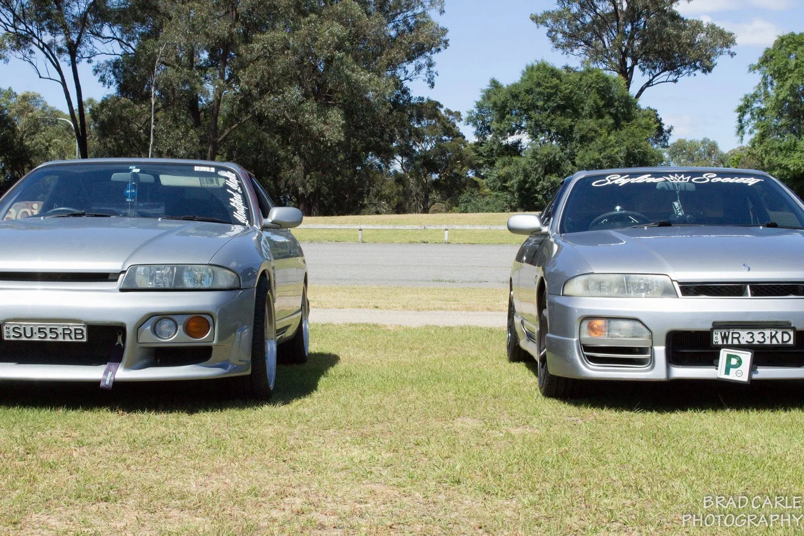 Two silver Skyline coupes parked on grass